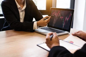 Financiero enseñando gráfica en portátil a cliente