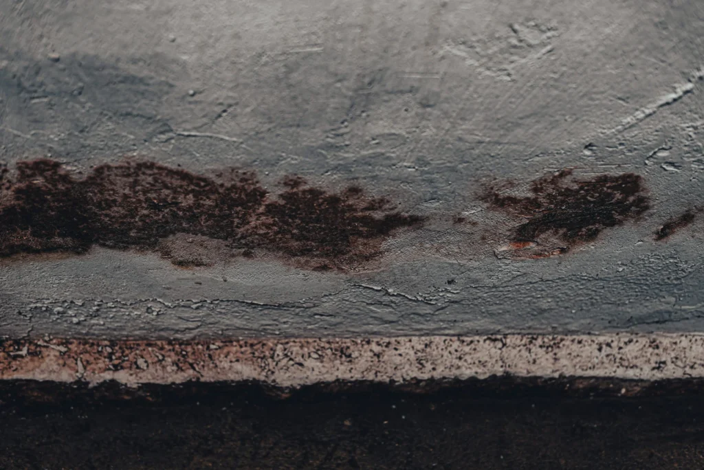 Manchas de humedad y moho en una pared con pintura deteriorada y signos de filtración.