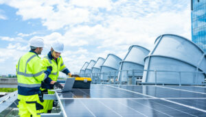 Técnicos con ropa de alta visibilidad instalando o revisando paneles solares en una planta de energía renovable industrial.