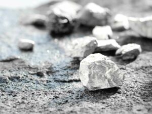 Fragmentos de mineral de platino sobre una superficie oscura, representando materias primas utilizadas en la industria metalúrgica.